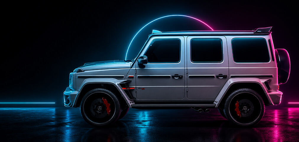 Side view of a silver Mercedes-Benz G-Class SUV in a dark studio, illuminated by blue and pink neon lights with a circular glow behind it.